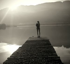 Rear view of people standing on lake against sky