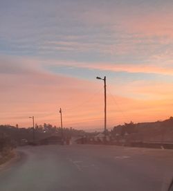 Silhouette electricity pylons against sky during sunset