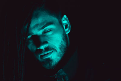 Close-up of young man with dreadlocks against black background