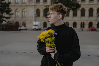 Side view of young woman holding bouquet