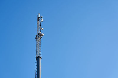Low angle view of communications tower against blue sky