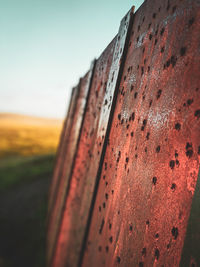 Close-up of rusty metal on field against sky