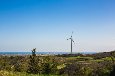 Wind turbines on land against clear blue sky