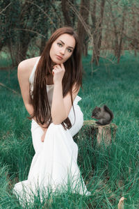 Beautiful young woman looking away while sitting on land