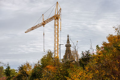 Low angle view of crane at construction site against sky