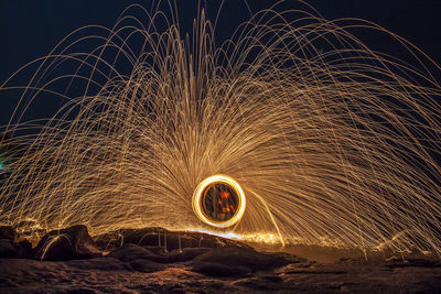 Low angle view of illuminated light trails against sky at night