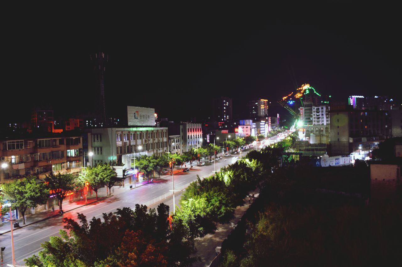 building exterior, city, architecture, built structure, night, illuminated, cityscape, tree, city life, street light, road, city street, residential building, residential district, building, sky, outdoors, office building, growth, modern, no people, tall - high, development