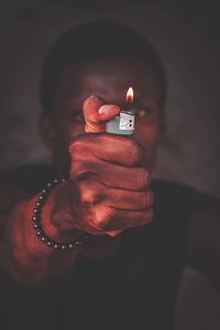 Close-up of man holding lit cigarette lighter