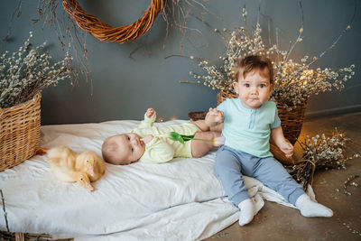 Two babies with small goslings eco style grey background wicker basket willow