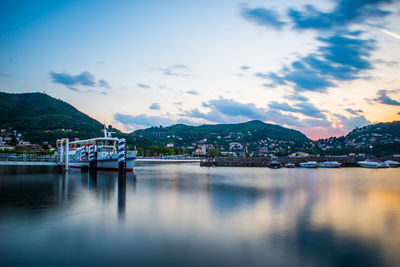 The city of como, in the evening, with the lakefront, the cathedral, and the surrounding mountains.