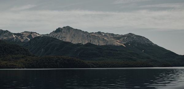 Scenic view of lake by mountains against sky