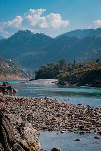 Scenic view of sea by mountains against sky