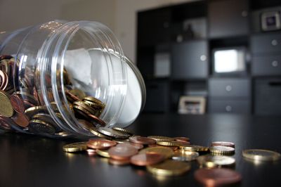 Close-up of currency spilling from jar jar on table