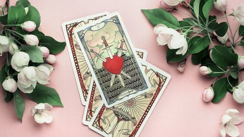 Tarot cards three of swords pink still life on table. esoteric concept and astrology