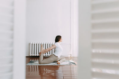 Side view of woman sitting on floor at home