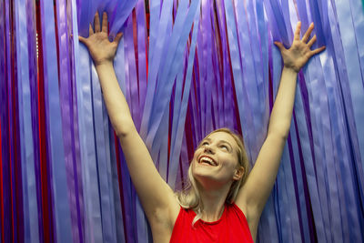 Smiling young woman standing against curtain