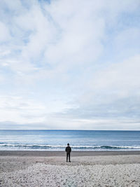 Woman standing on beach against sky