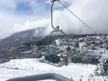 Ski lift over snow covered land against sky