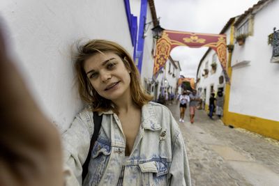 Portrait of smiling woman by wall standing on street