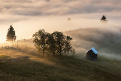 Hut on mountain against cloudy sky