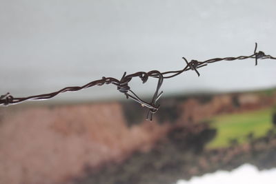 Close-up of barbed wire fence against sky