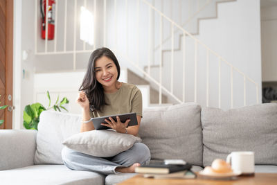 Young woman using mobile phone while sitting at home