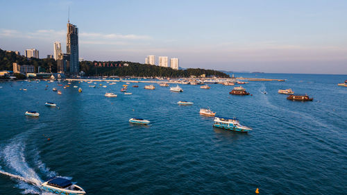 Sailboats in sea by buildings against sky