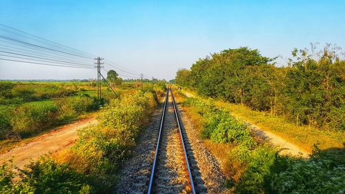 Railroad tracks by trees against clear sky