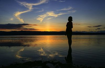 Silhouette man standing on beach against sky during sunset