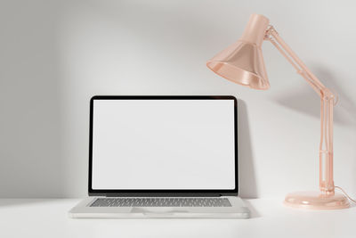 Close-up of electric lamp on table against white background