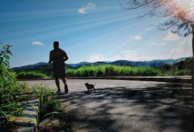 Rear view of man with dog against sky