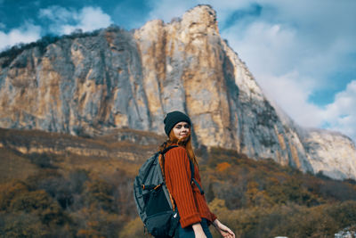 Portrait of young woman standing on rock against mountains