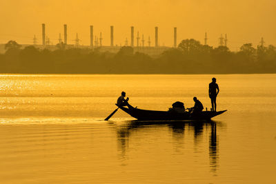 Silhouette people on boat in sea against sky during sunset