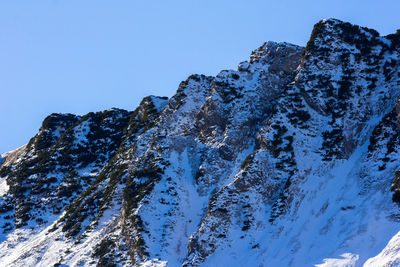 Low angle view of snowcapped mountain against blue sky