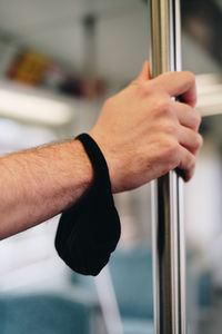 Close-up of hand holding pole in train