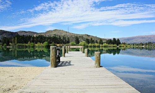 Wooden pier over lake against sky