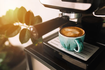 Green cup of coffee at the coffee maker machine, coffee time. blurred background. high quality photo