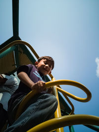 Portrait of boy sitting against sky