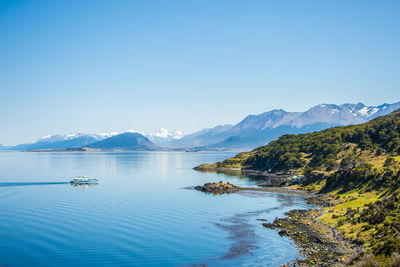 Scenic view of sea and mountains against clear blue sky