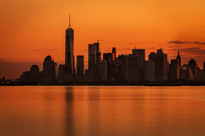 East river by city skyline against orange sky