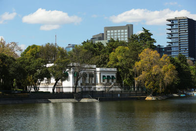 Building by river against sky in city