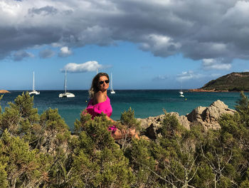 Young woman by sea against sky