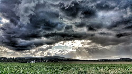 Scenic view of field against storm clouds