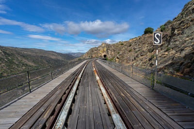 Railroad tracks leading towards mountain against sky