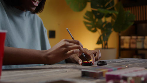 Midsection of woman using mobile phone at table