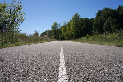 Empty road leading towards trees on field