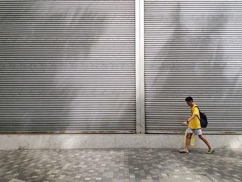 Full length of man running on footpath against wall