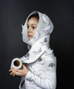 Portrait of young woman wearing mask against black background