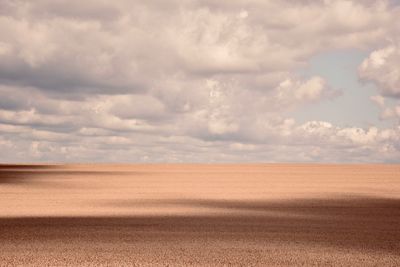 Scenic view of field against cloudy sky