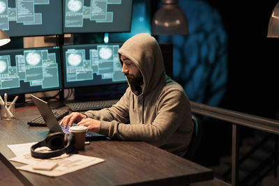 Rear view of man using laptop at table